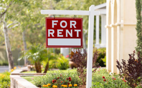 Red For Rent Real Estate Sign in Front House.