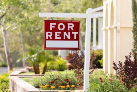 Red For Rent Real Estate Sign in Front House.